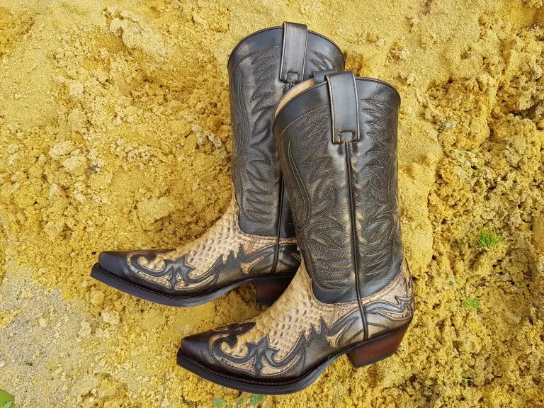 Cowboy boots on yellow sand showing classic Western leather details.